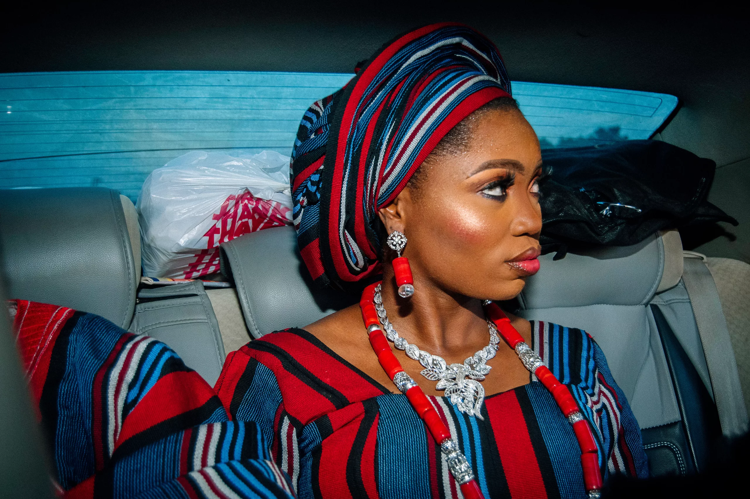 yoruba bride wearing aso oke looks out the car window